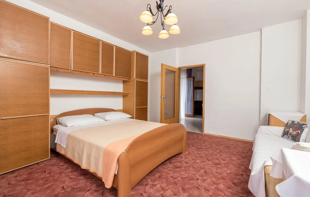 A bedroom with a bed, built-in wooden cabinets, and a small seating area.