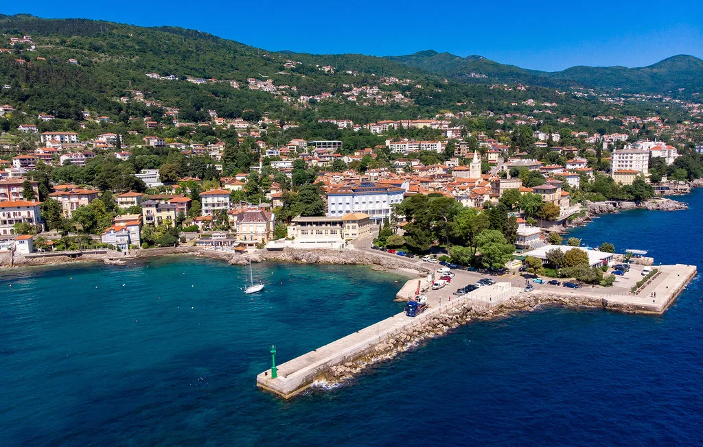 A coastal town stretches along a sheltered bay, with a pier extending into the water.