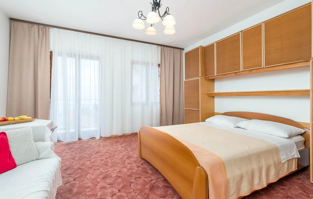 A bedroom with a bed, seating, and curtained windows.