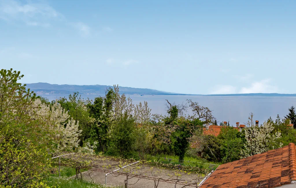 A leafy garden and rooftops overlook a broad expanse of water.