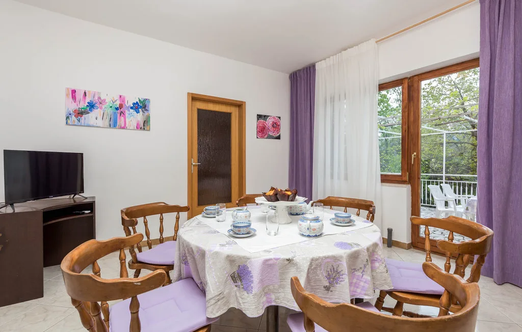 A dining area with a round table set beside a large window.