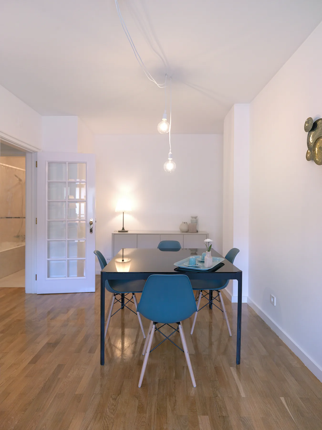 Comedor con una mesa, asientos azules y una puerta con paneles de vidrio.