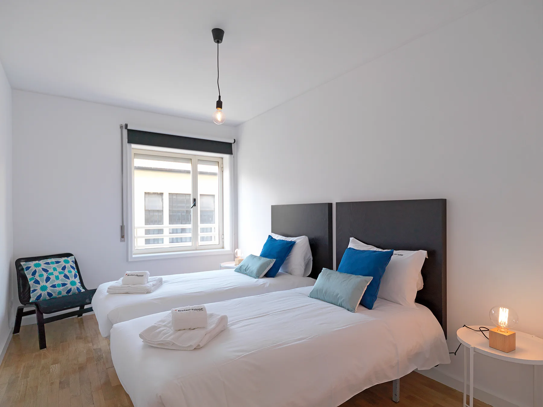 Un dormitorio con dos camas, cojines azules y una ventana.