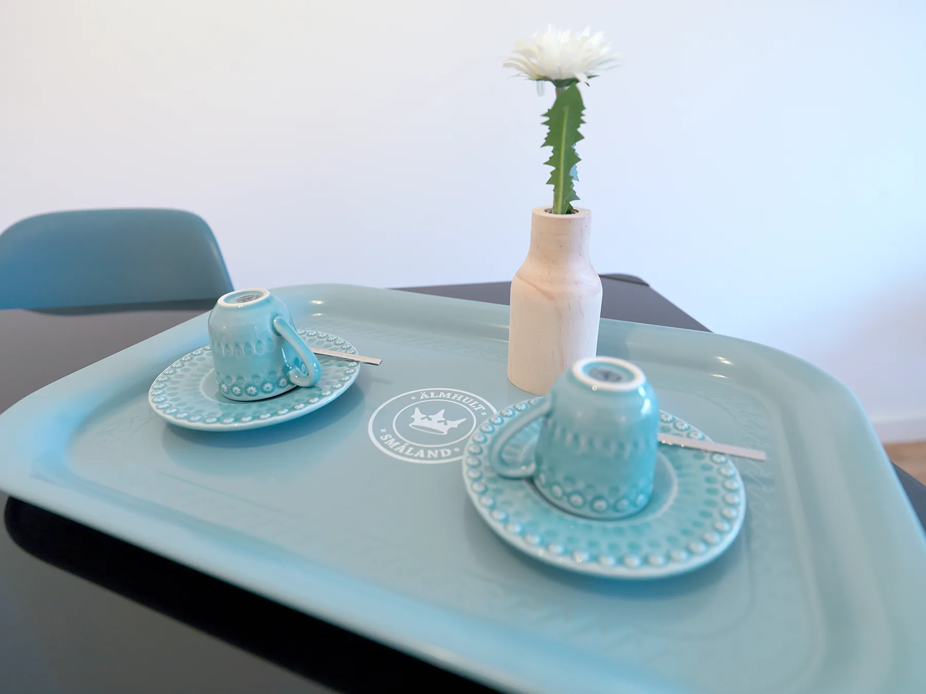 Una mesa de comedor tiene dos tazas con platillos junto a un pequeño florero.