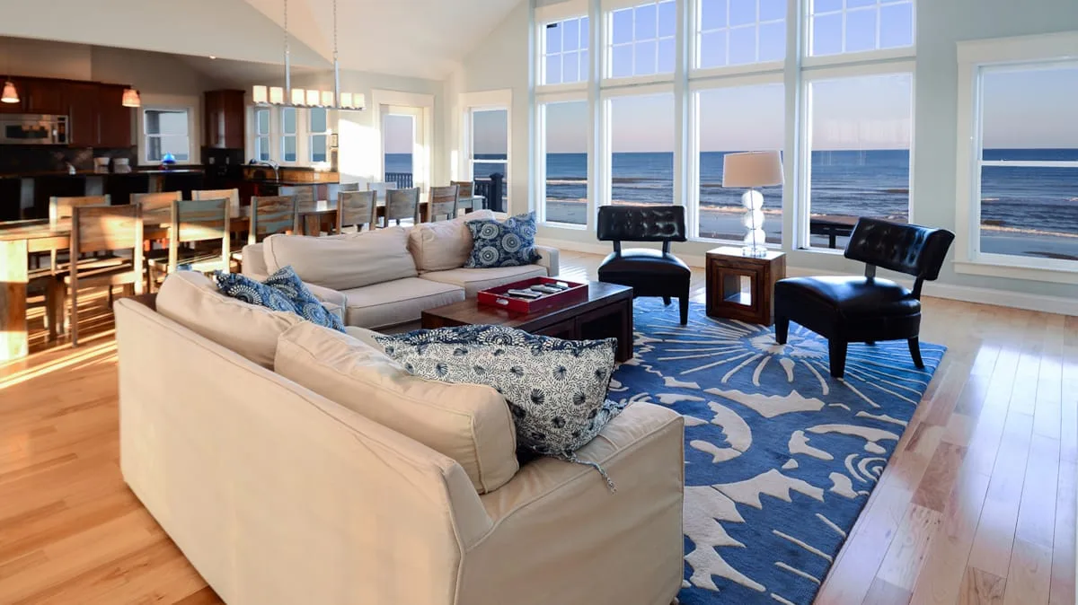 A bright living room with seating and large windows overlooking the ocean.