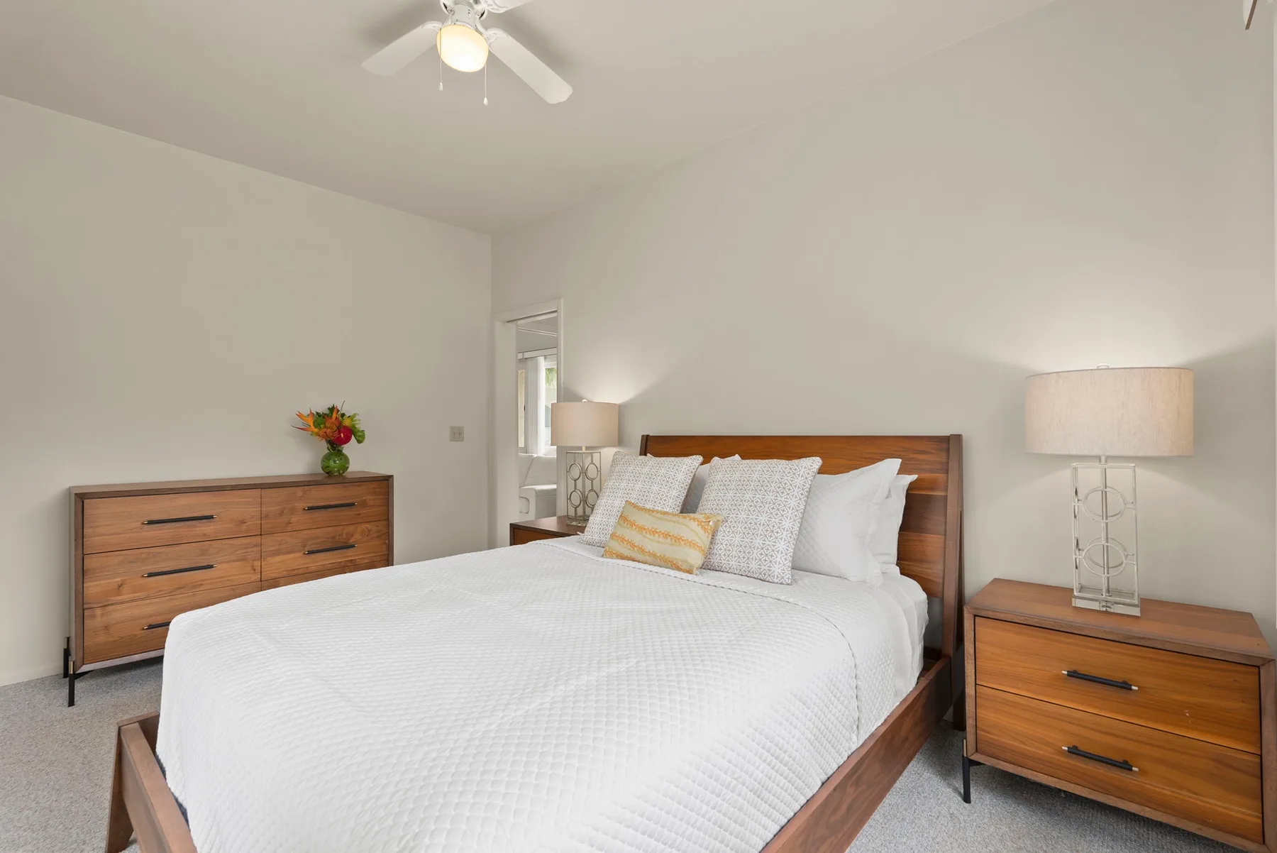 A bedroom with a neatly made bed and matching wooden bedside furniture.
