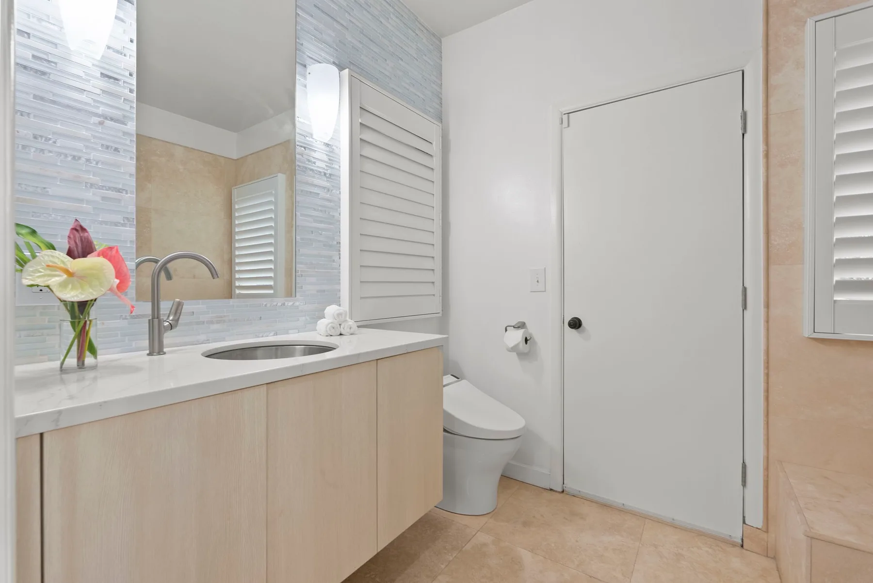 A bathroom vanity and sink are beside a toilet and a closed door.