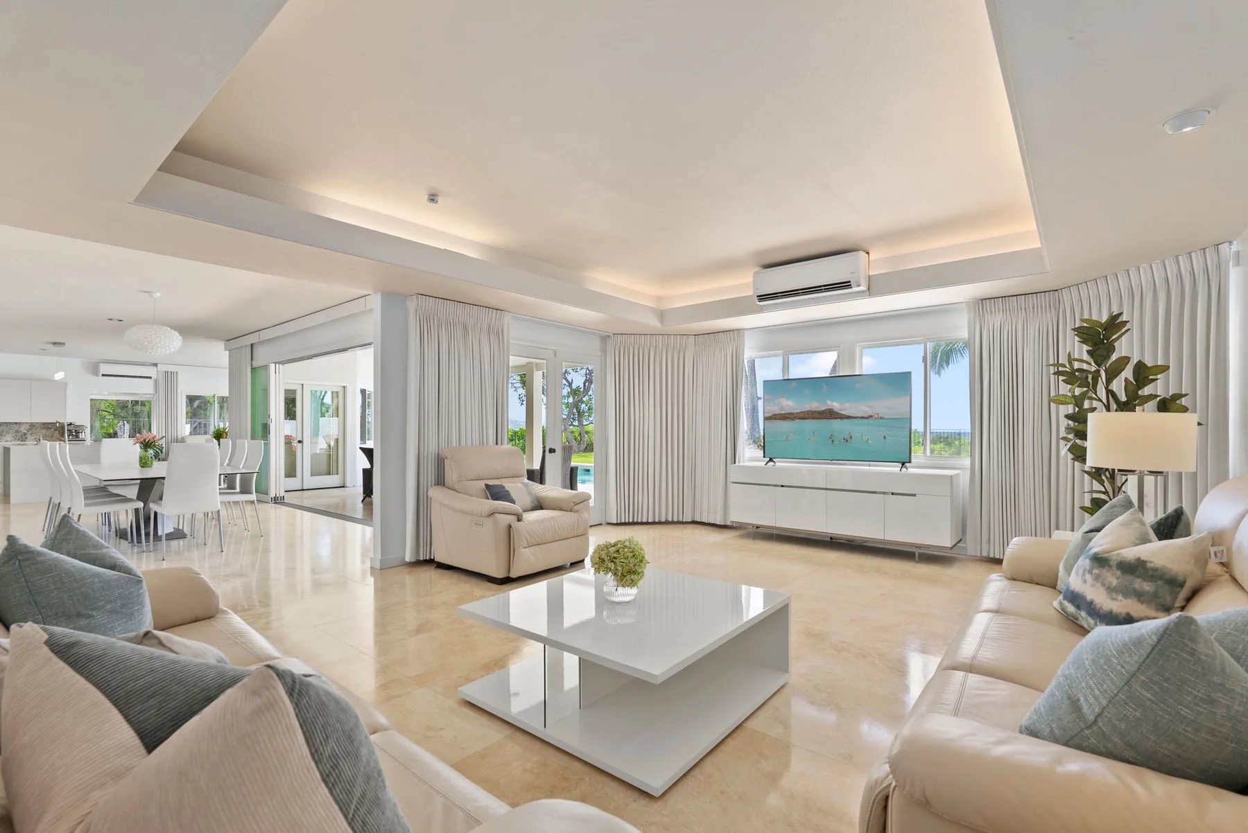 A bright living room with seating, a coffee table, and wide windows.
