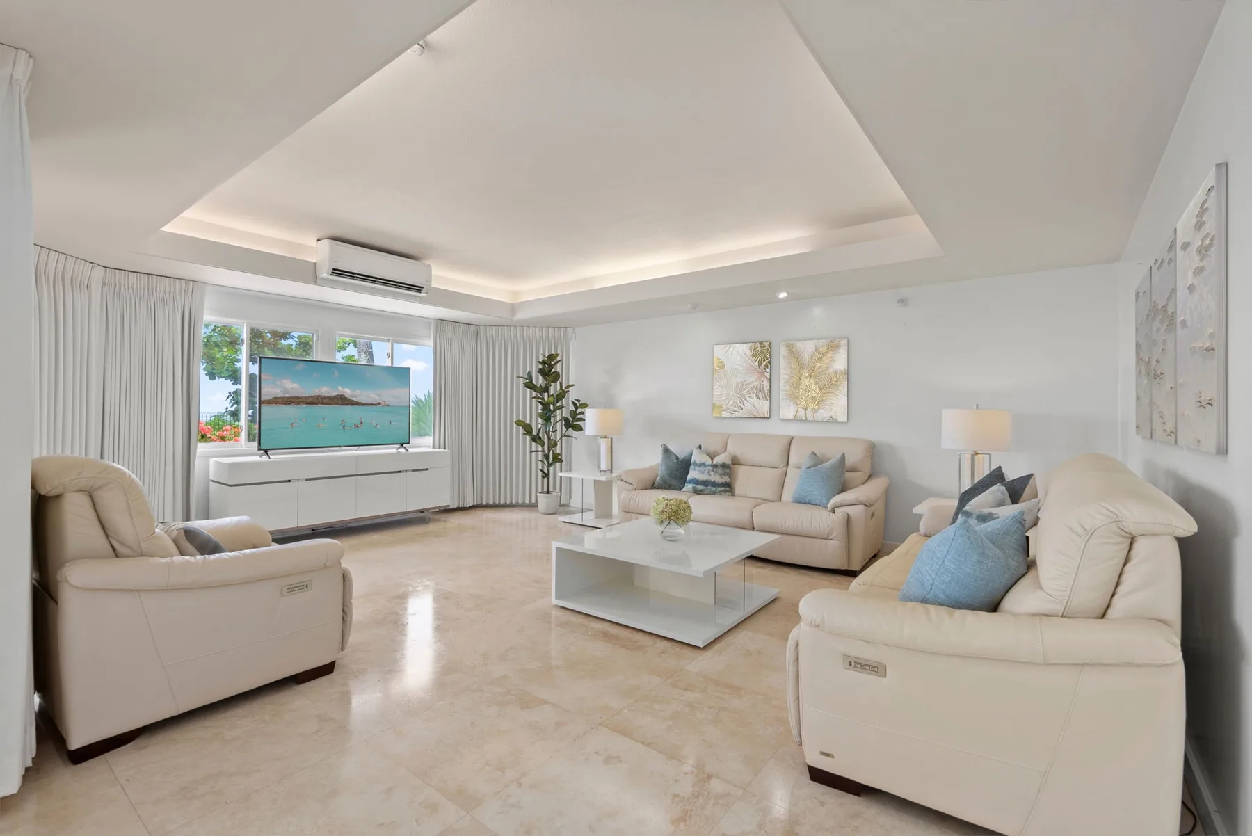 A bright living room with light-colored seating and a television.