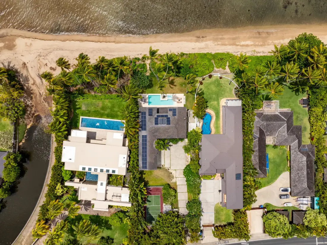 Aerial view of beachfront buildings, pools, and landscaped grounds.