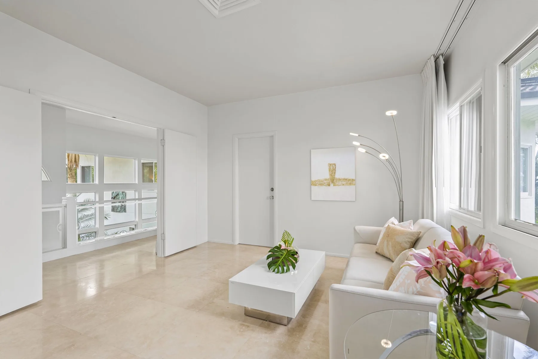 A bright living room with seating beside large windows and a white coffee table.