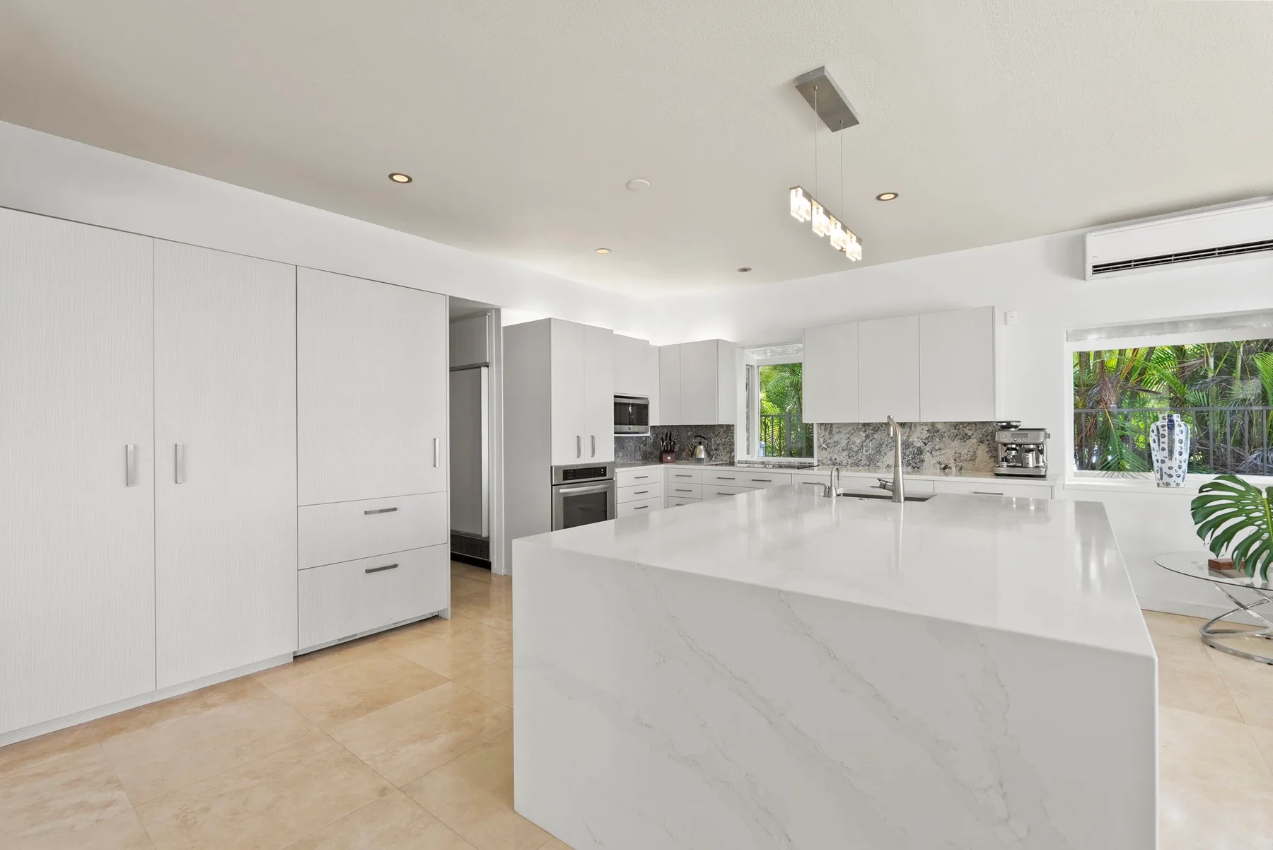 A bright modern kitchen with white cabinetry and a large central island.