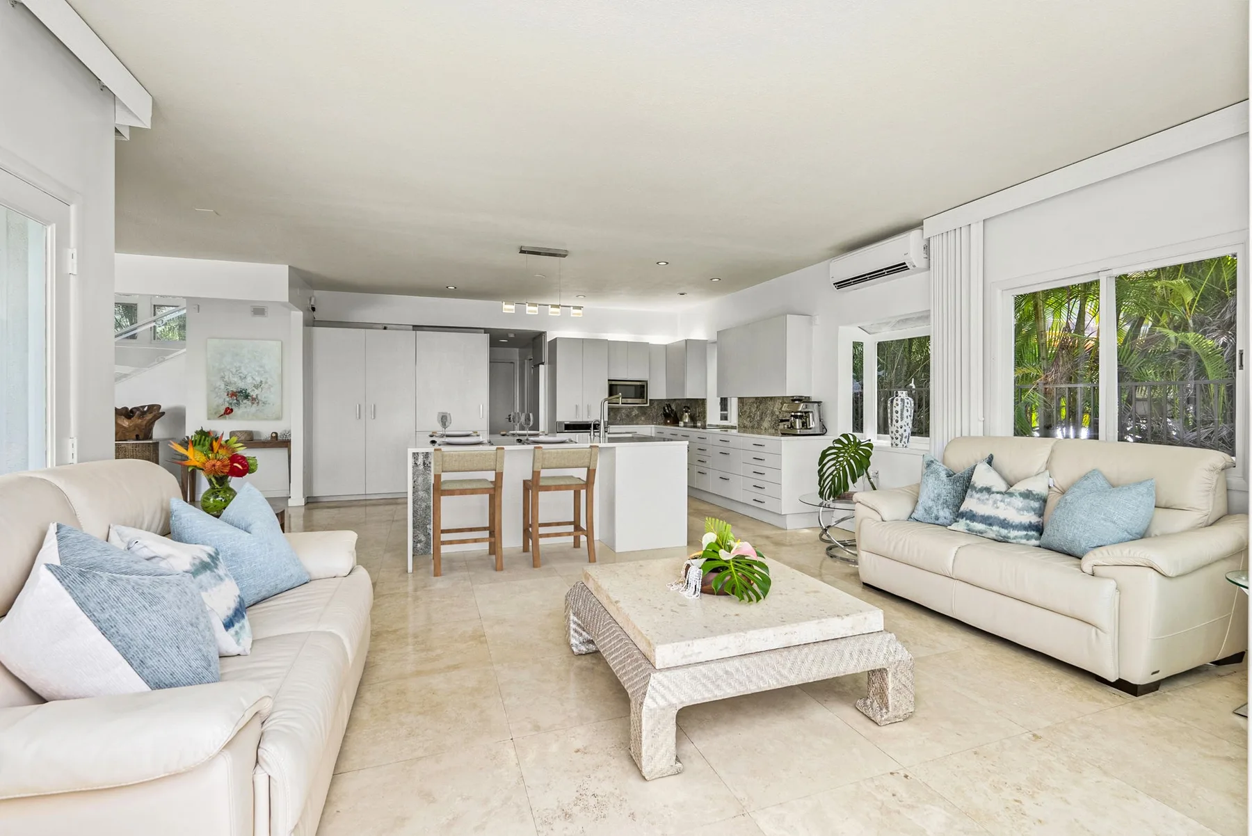 A bright open-plan living room with seating around a low coffee table.