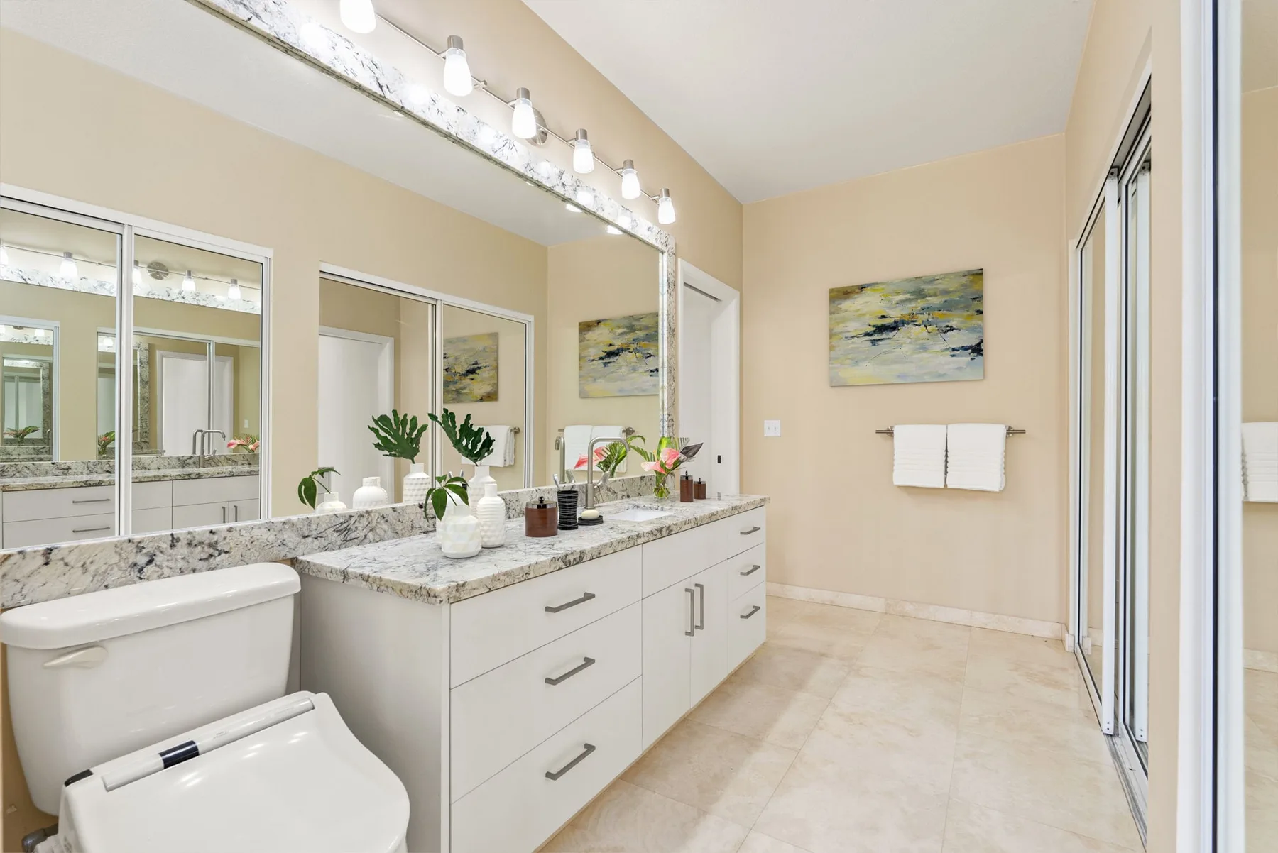A bright bathroom with a long vanity, mirror, and wall-mounted towel bar.