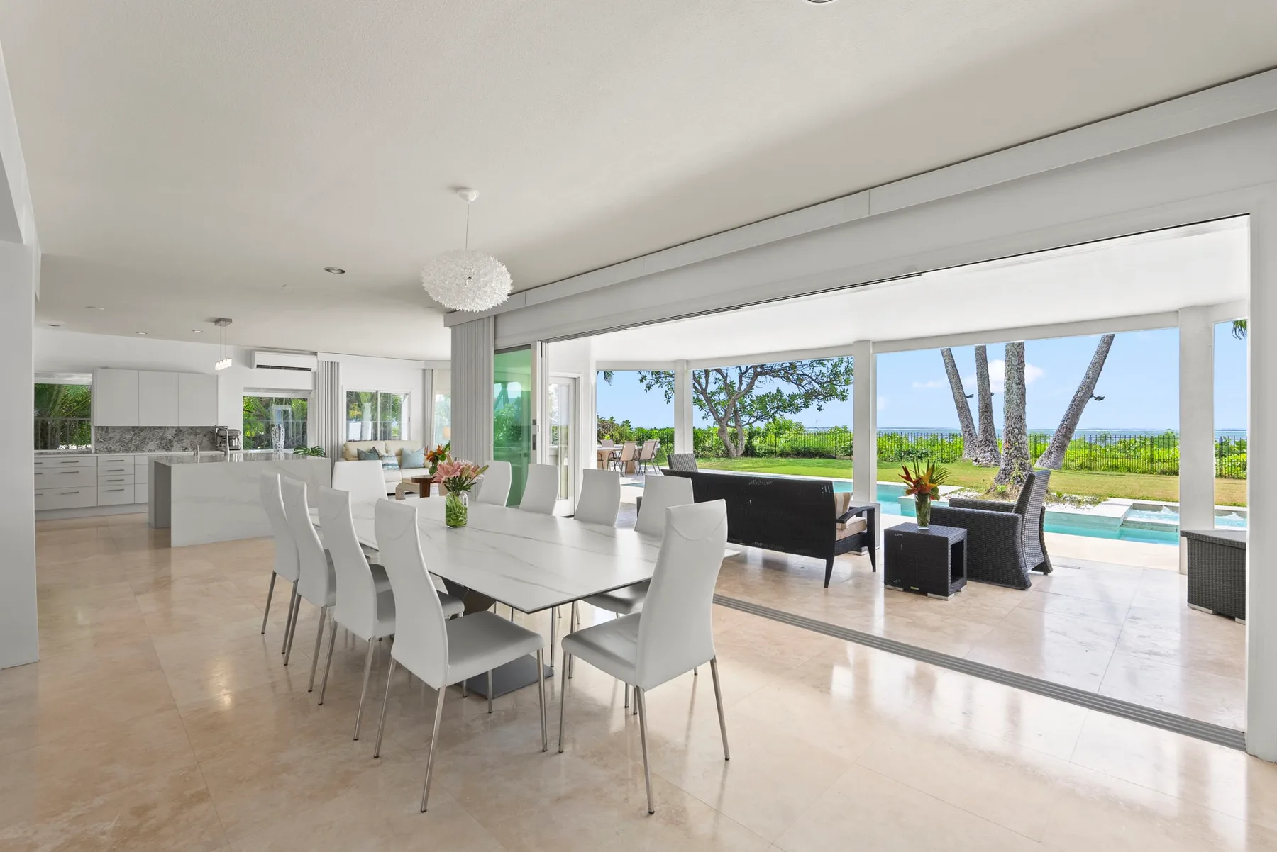 Un comedor y sala de estar de planta abierta dan a un patio con piscina y vistas al mar.