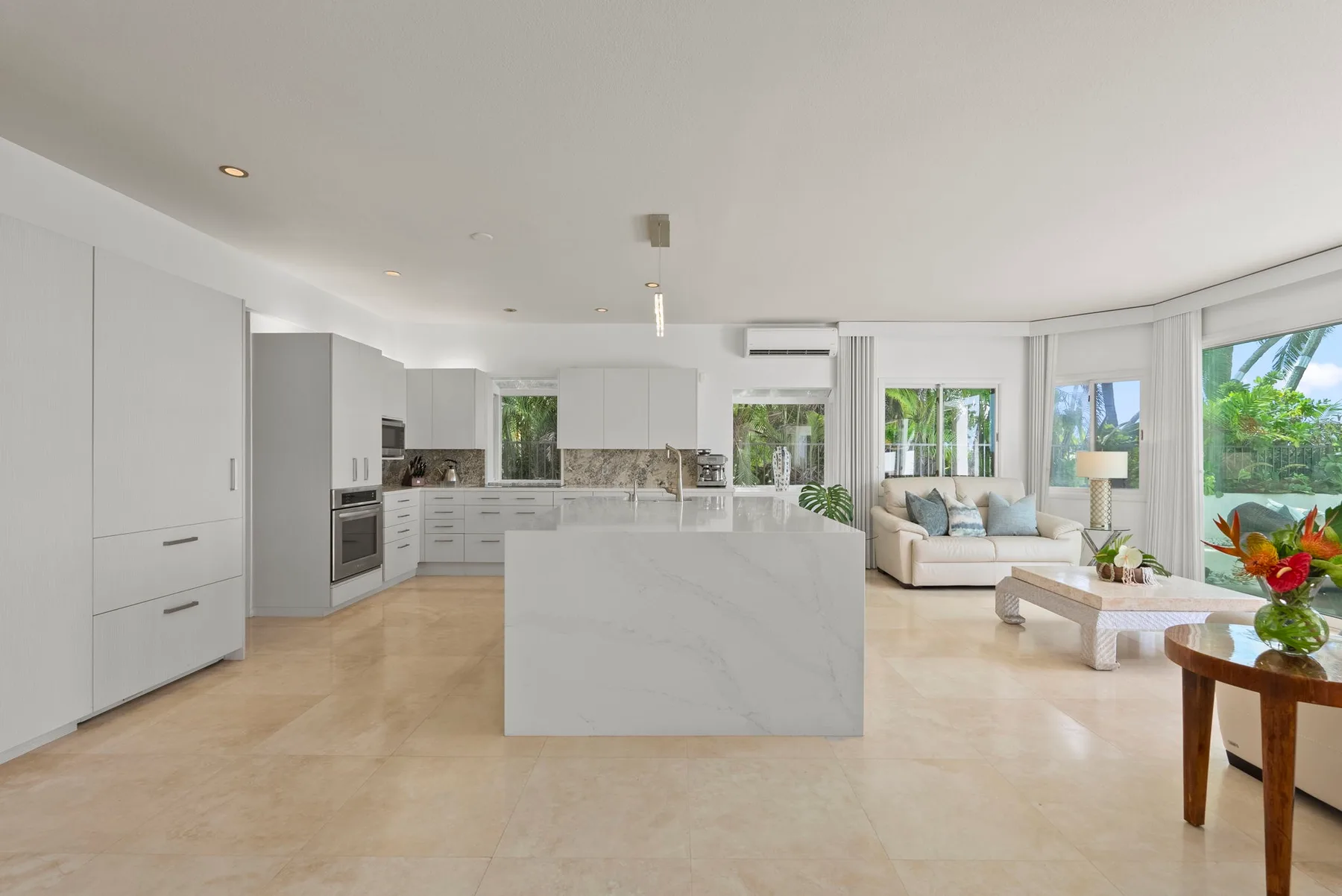 An open-plan kitchen and living area with a central island and large windows.