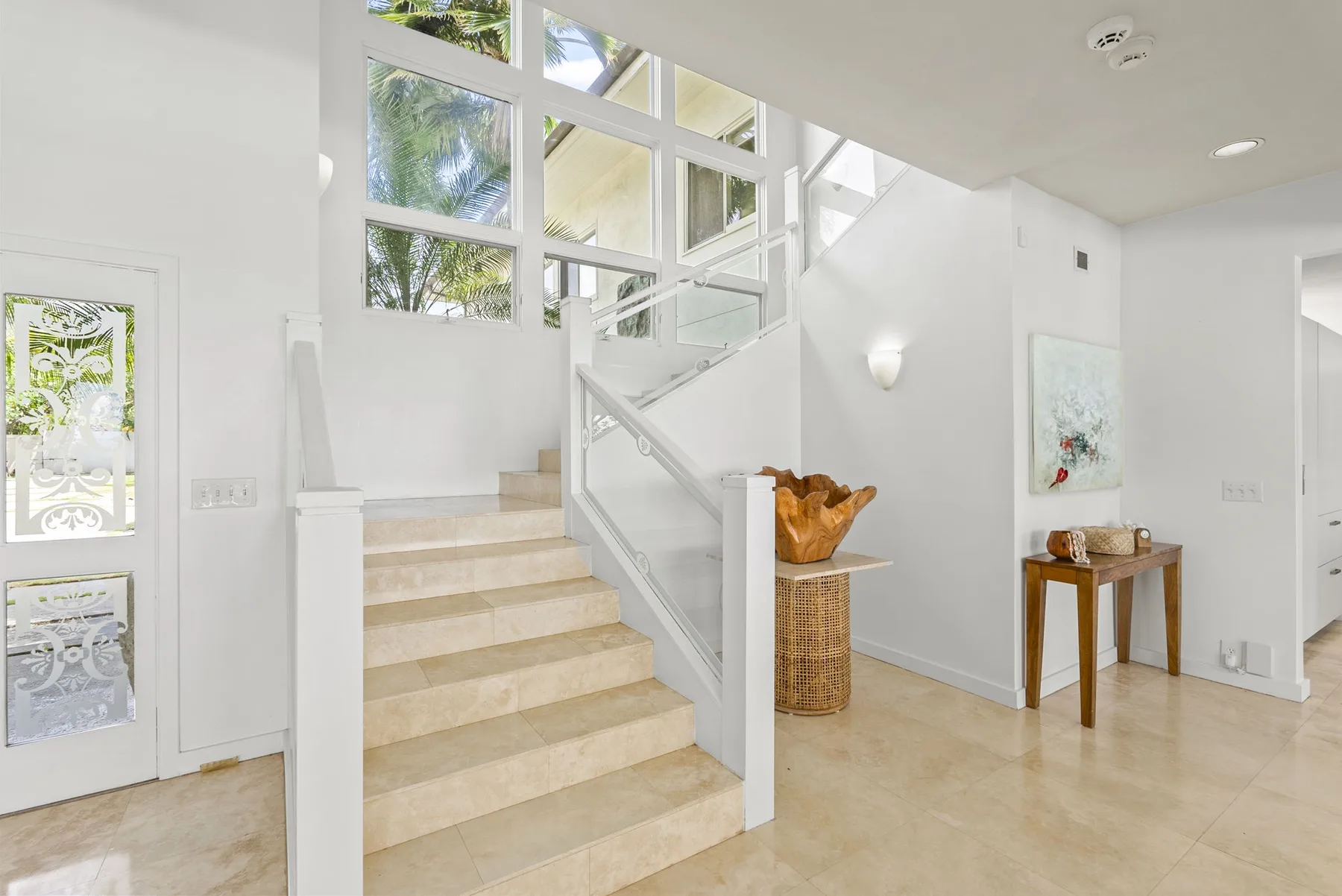 A bright stairwell with a white railing and large windows.