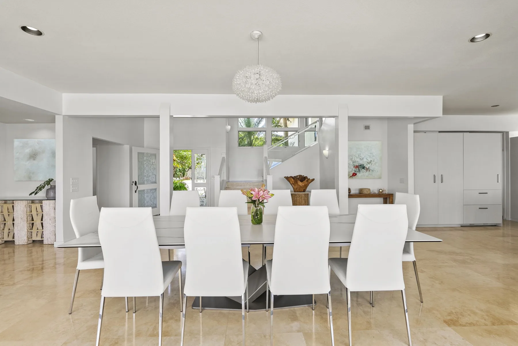 A bright dining area with a long table and white seating.