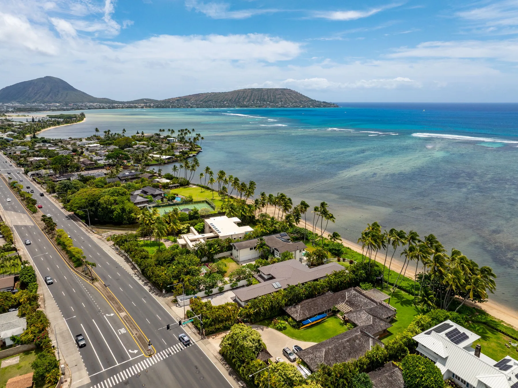 Aerial view of a coastal neighborhood beside a broad turquoise bay.