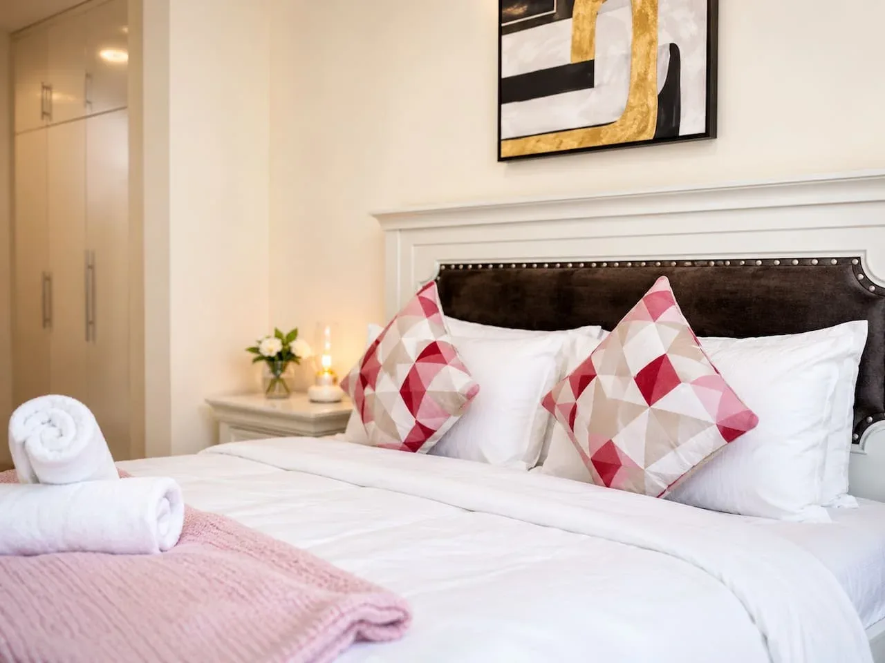 A bedroom with a neatly made bed and patterned accent pillows.