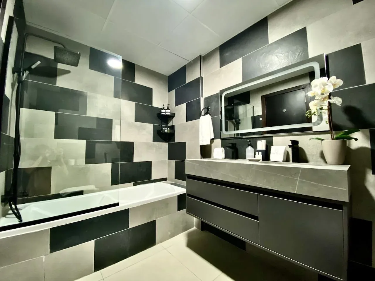 A modern bathroom with a bathtub and a wide vanity beneath a mirror.