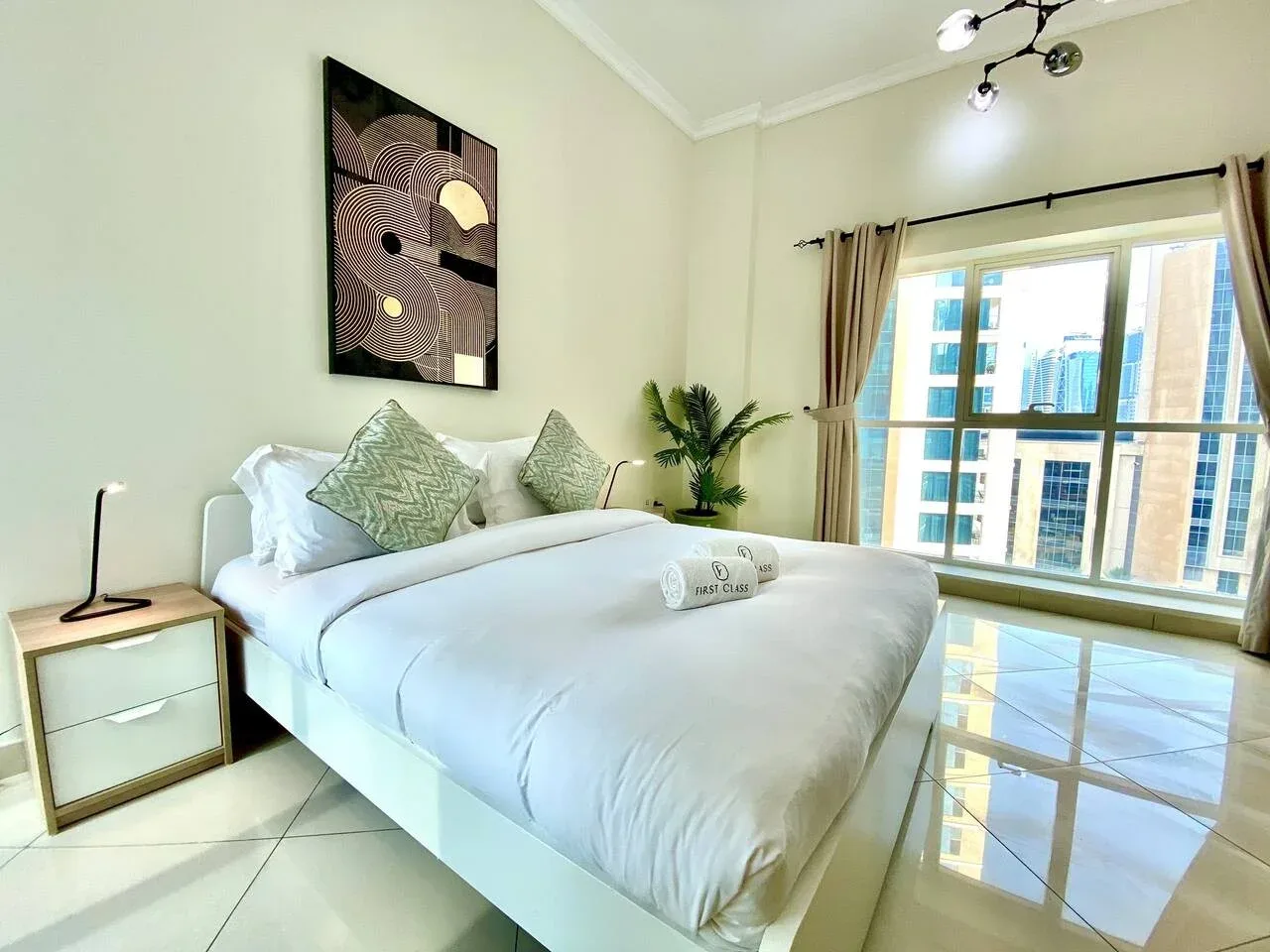 A bright bedroom with a neatly made bed beside large windows.