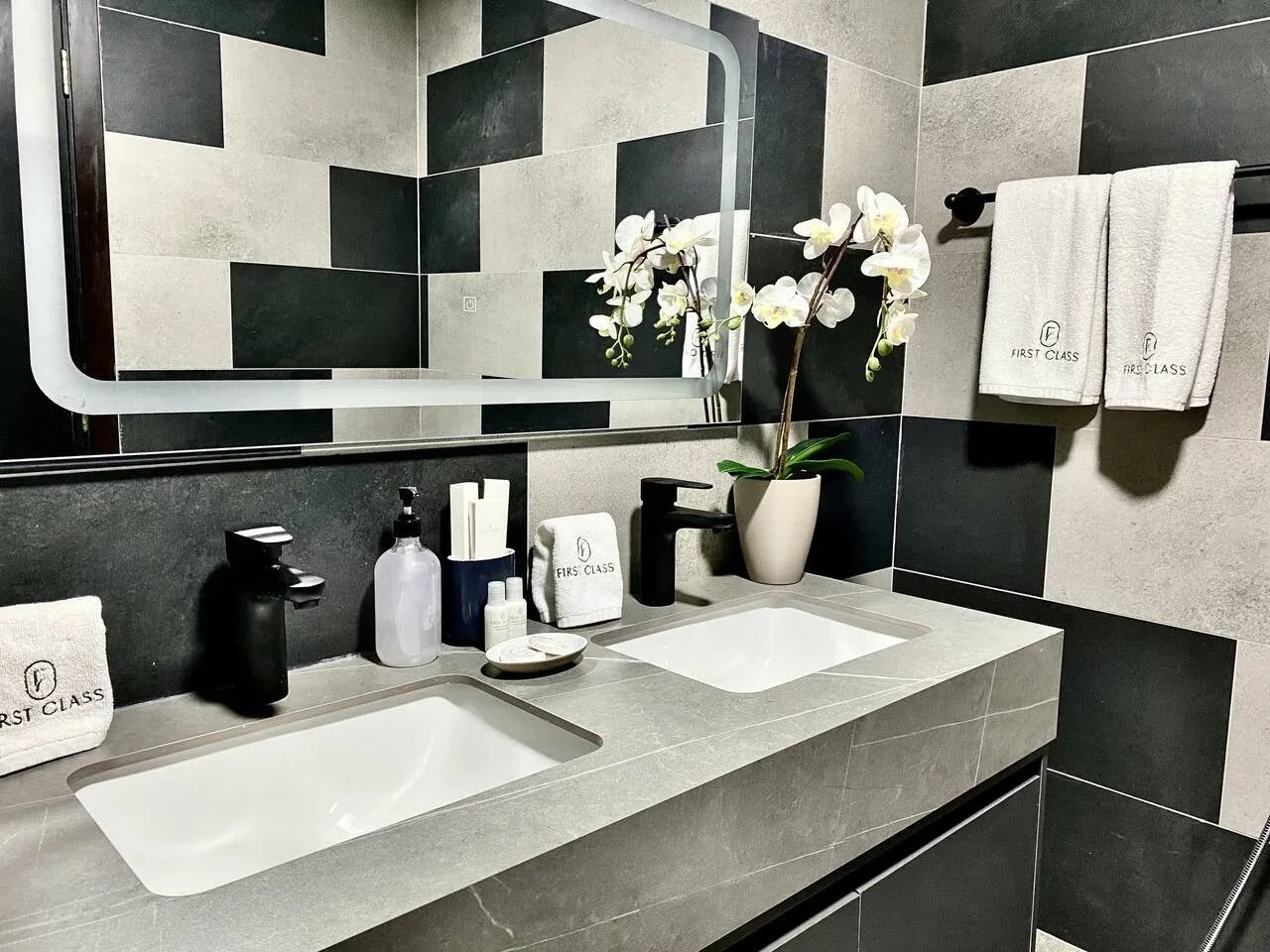 A bathroom vanity with two sinks, a large mirror, and a potted orchid.