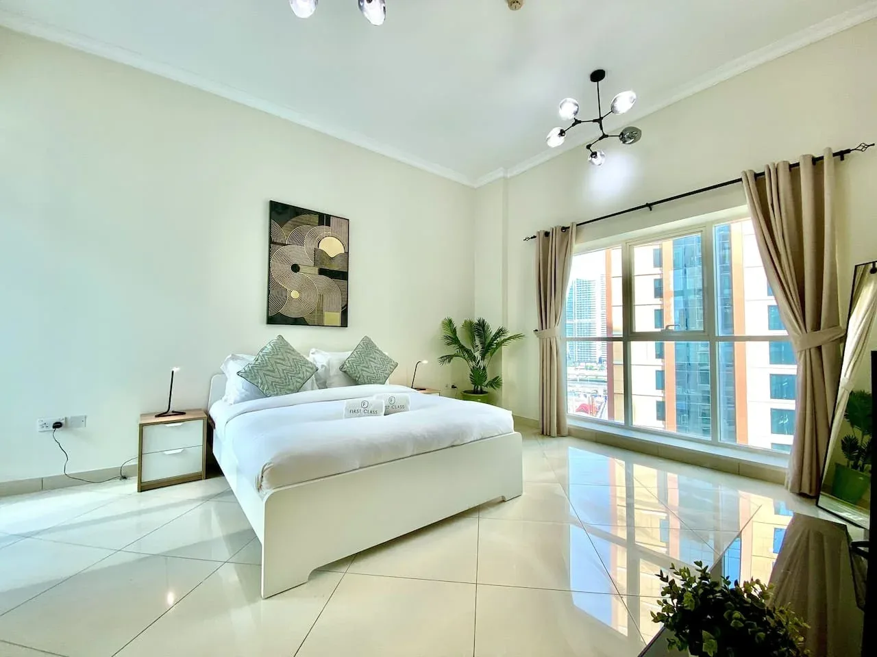 A bright bedroom with a neatly made bed beside large windows.