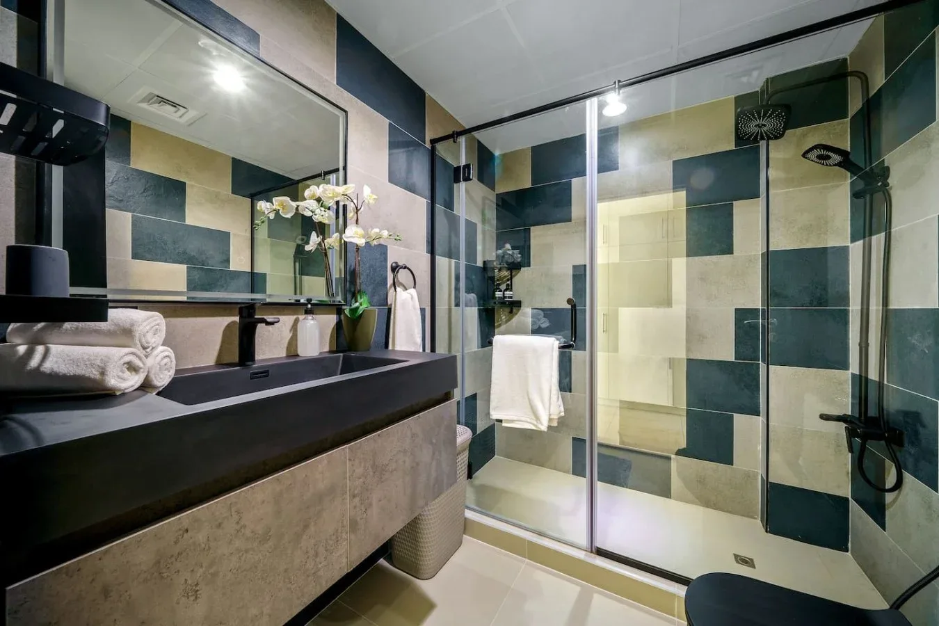 A modern bathroom with a glass-enclosed shower and a long vanity.