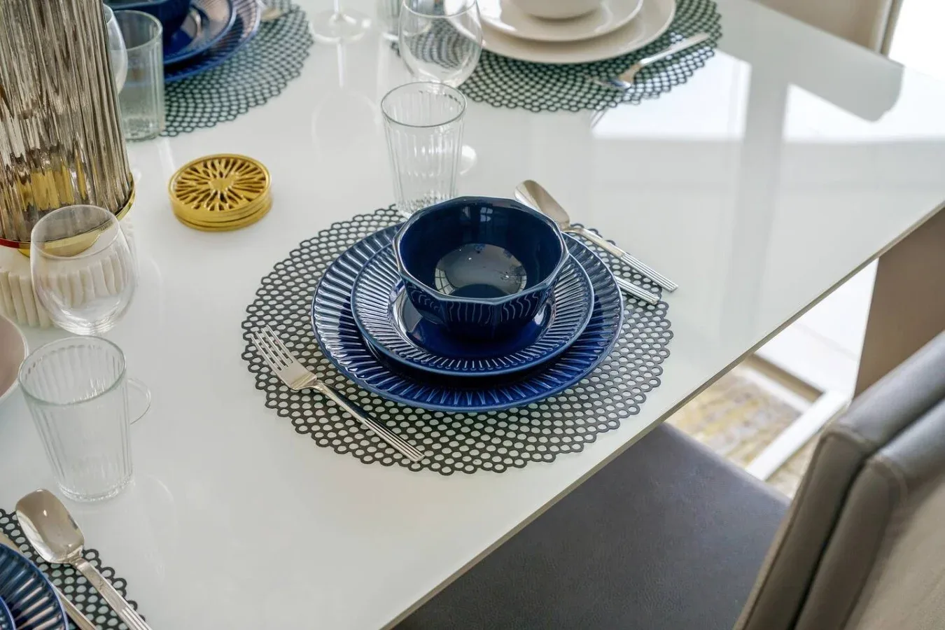 A dining table is set with blue plates and glassware.