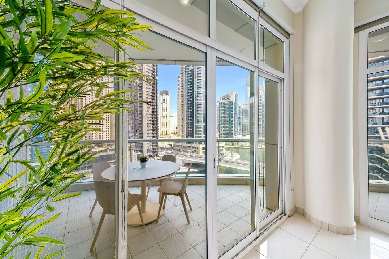 A bright dining area opens onto a balcony with a city view.