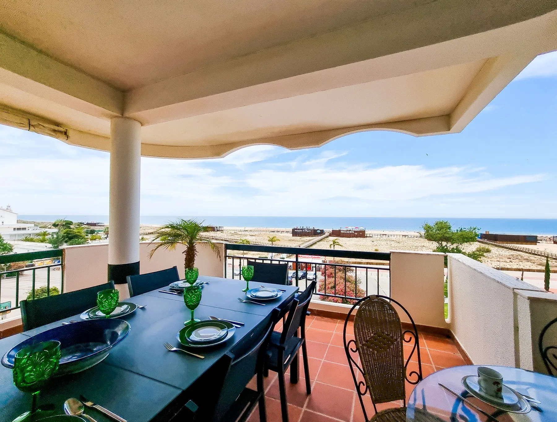 A covered balcony dining area overlooks the beach and sea.