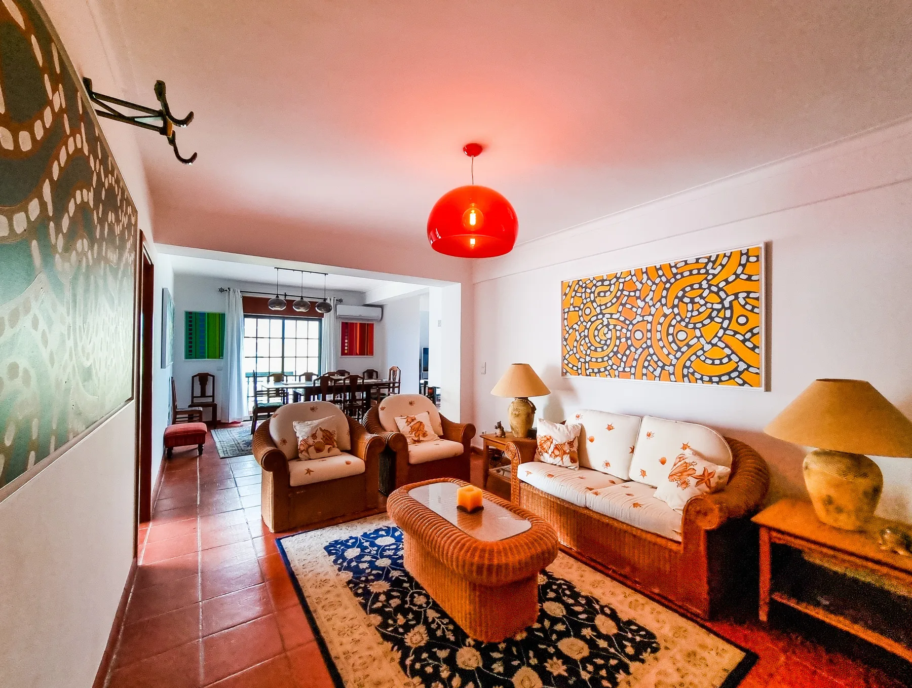 A living room with seating, a patterned rug, and colorful wall art.