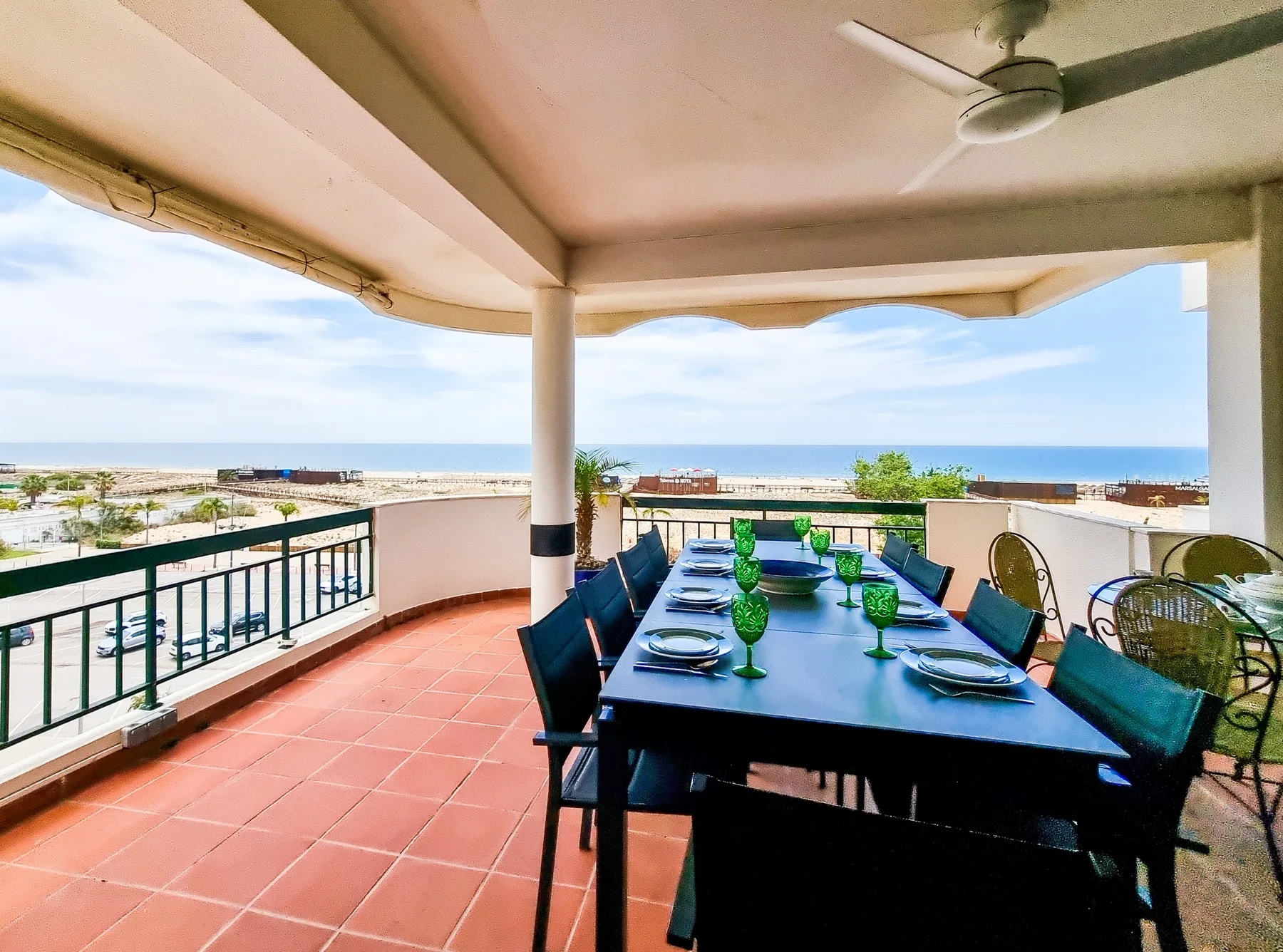 A covered terrace with a dining table overlooks the beach and sea.
