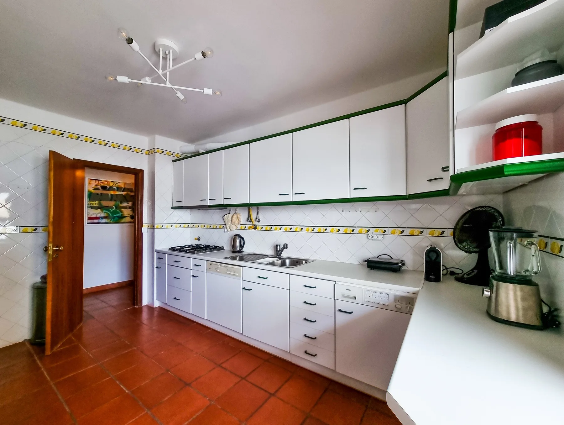 A bright kitchen with white cabinets and a long countertop.