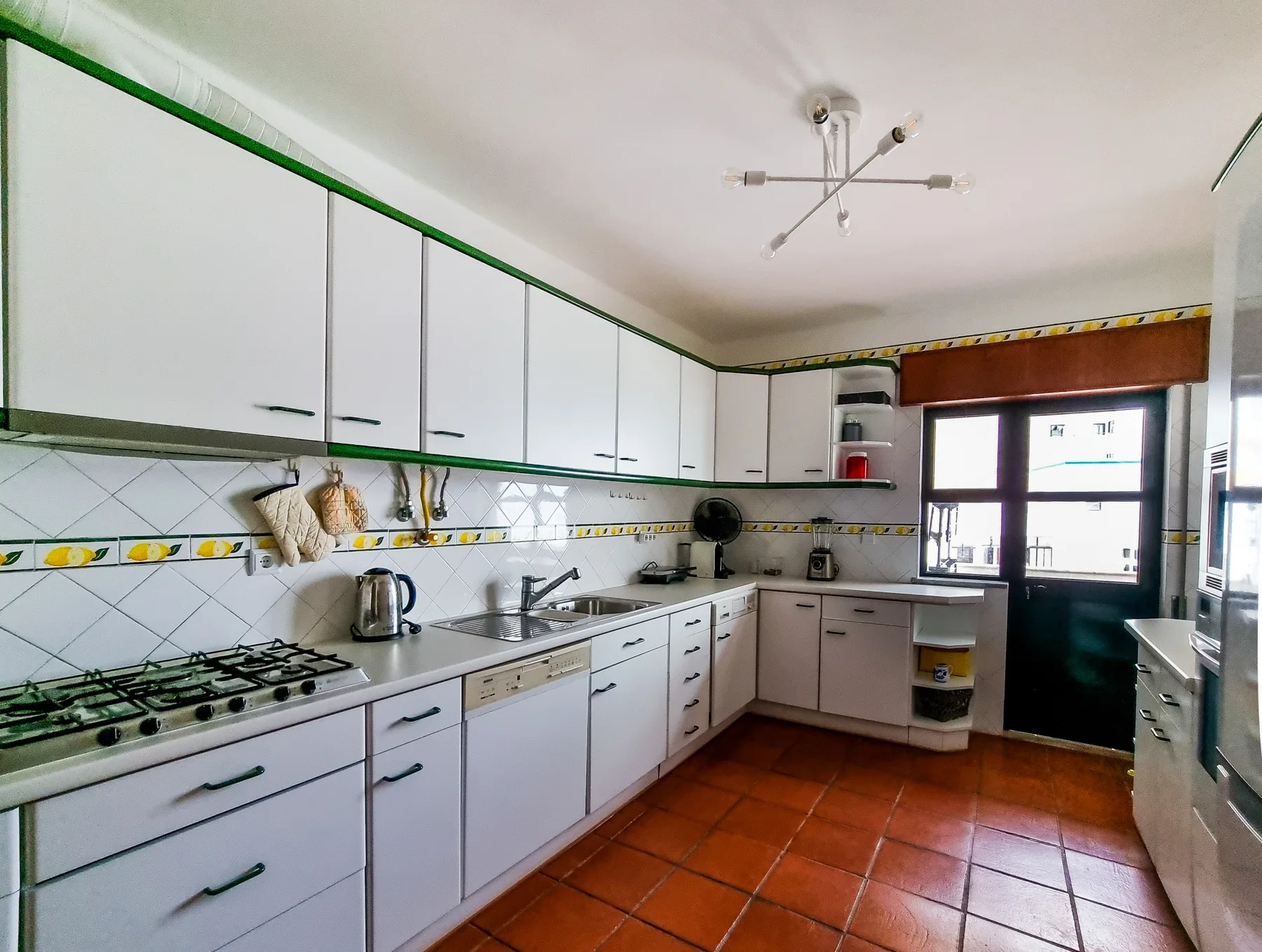 A kitchen with white cabinets, a cooktop, and a sink.