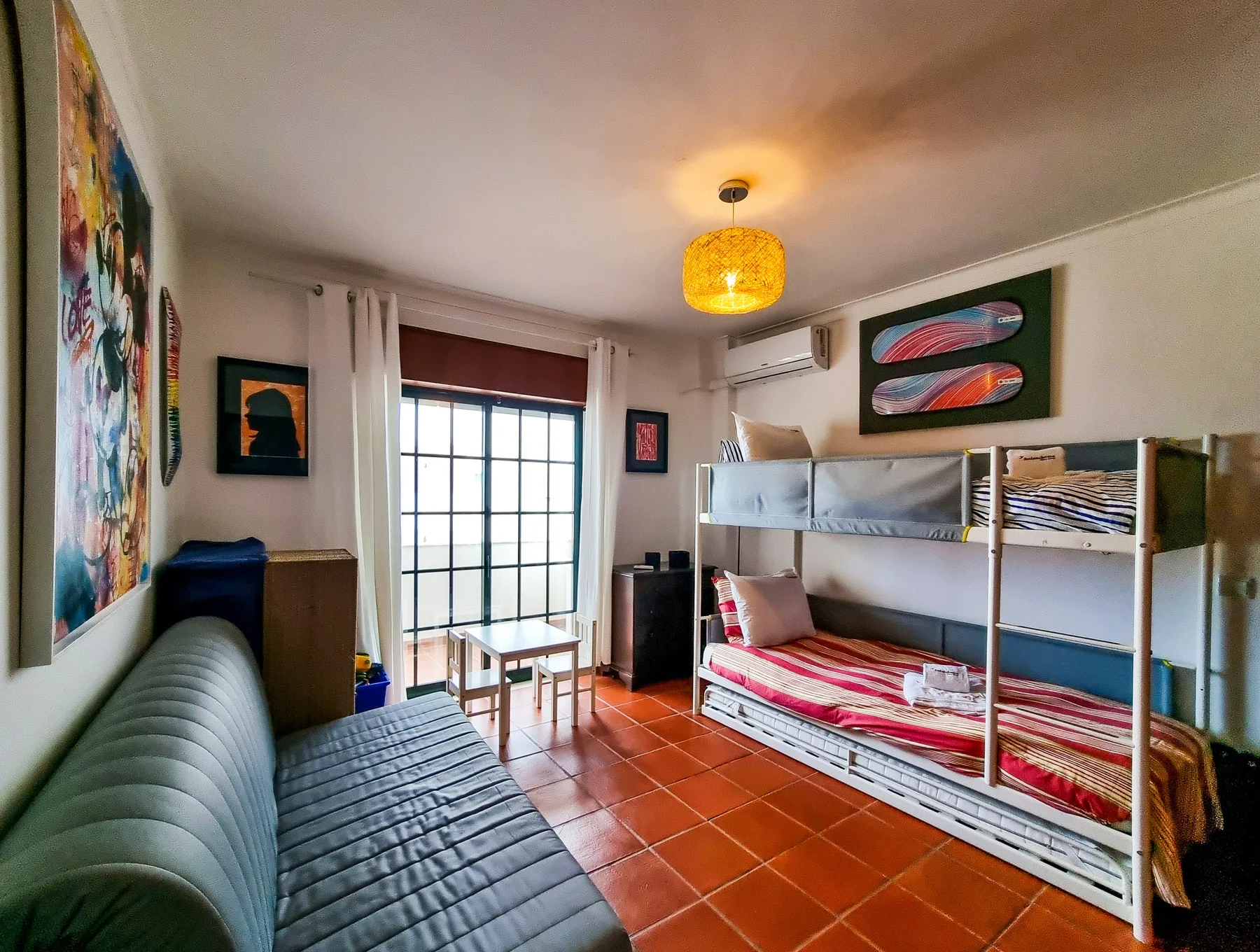 A bedroom with bunk beds and a seating area beside a large window.