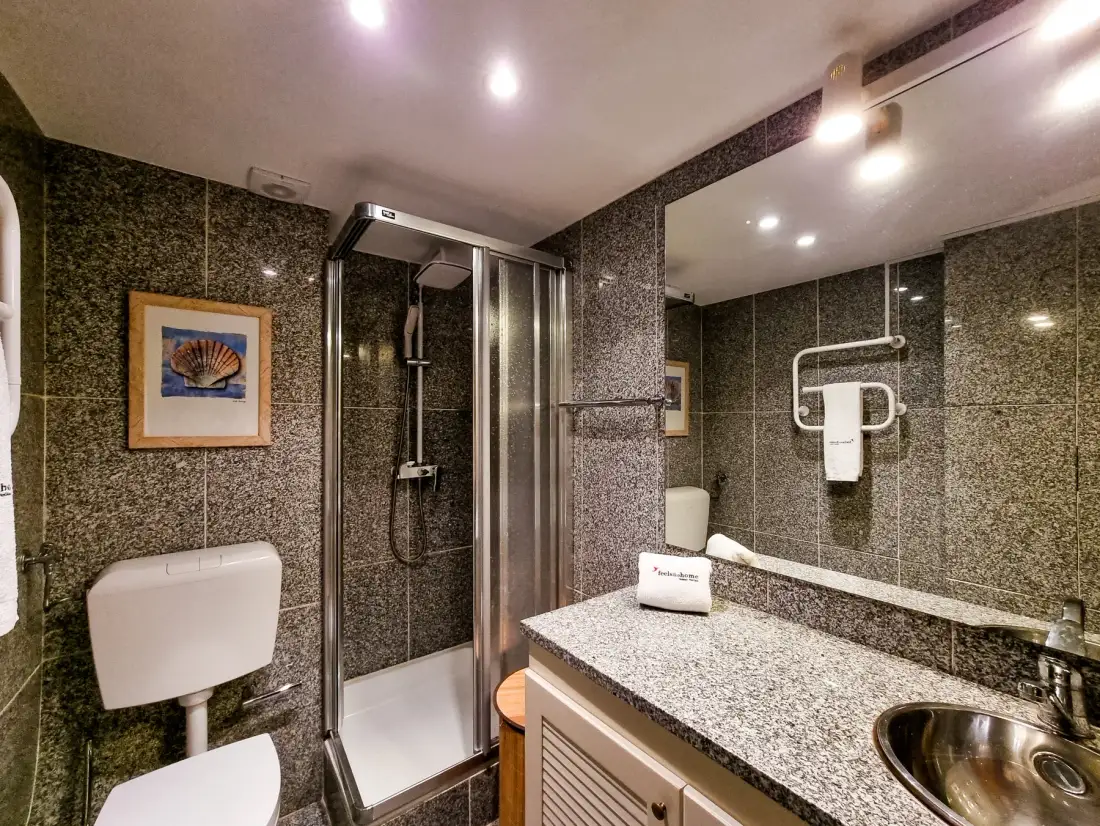 A bathroom with a glass shower, wall mirror, and long vanity counter.