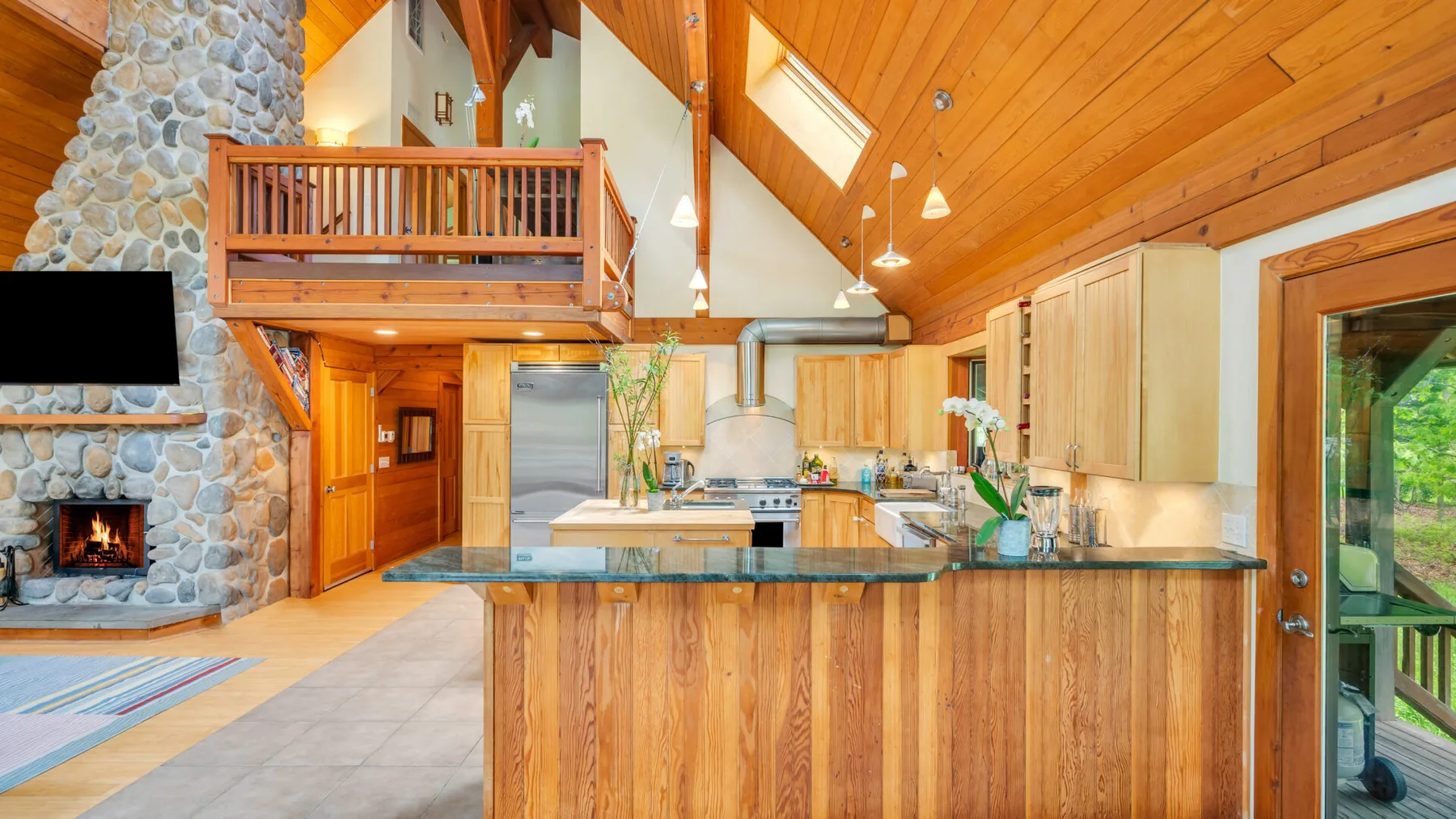 Una cocina revestida de madera con una isla central y una chimenea de piedra.