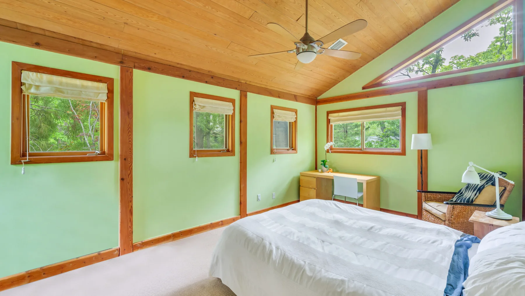Un dormitorio con una cama, ventanas y un techo de madera.