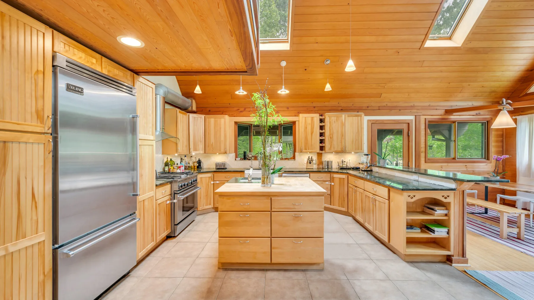 Una amplia cocina revestida de madera, con una isla central y un refrigerador de acero inoxidable.