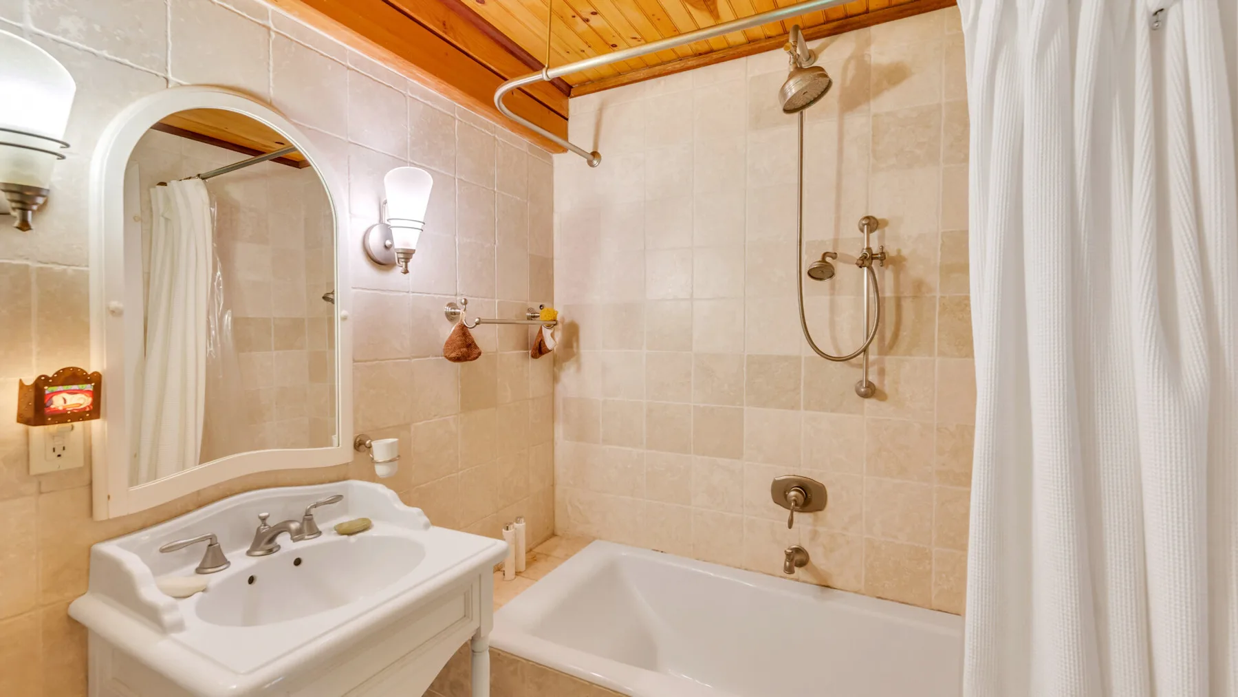 Un baño alicatado con bañera, ducha y lavabo.
