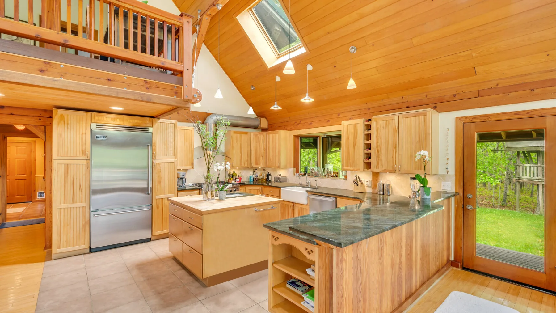 Una cocina revestida de madera con una isla central y puertas de vidrio que dan al jardín.