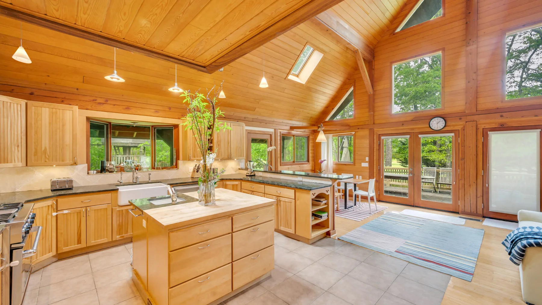 Una amplia cocina revestida de madera, con una isla central y grandes ventanas.