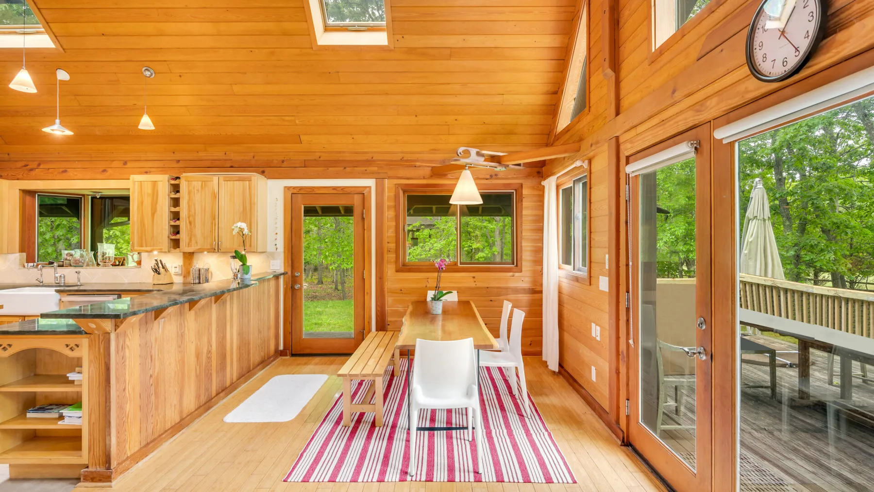 Una cocina y comedor con paneles de madera dan a una terraza a través de puertas de vidrio.