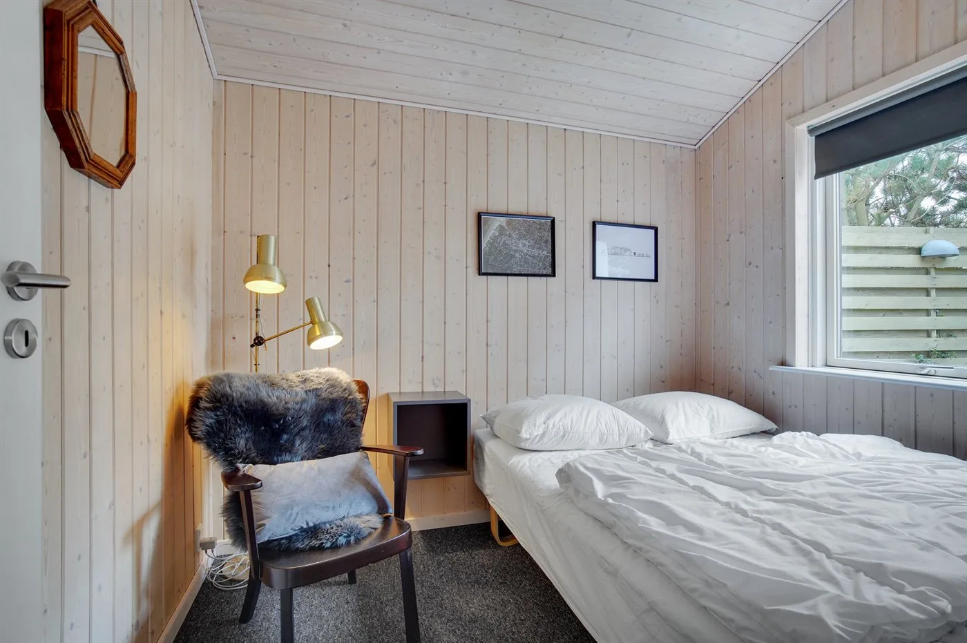 Un dormitorio con una cama, una silla y una ventana.