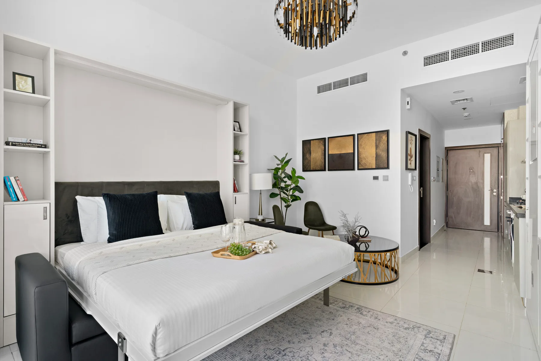 Un dormitorio luminoso con una cama grande, estanterías empotradas y una pequeña zona de estar.
