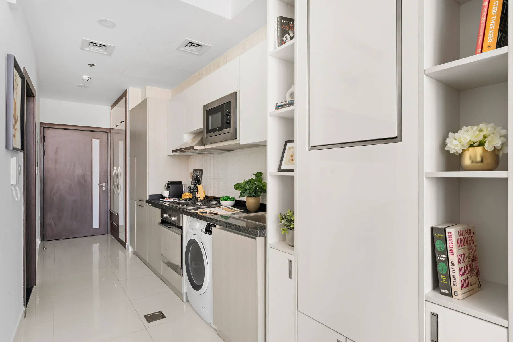Una cocina estrecha con encimera, electrodomésticos y estantes abiertos.