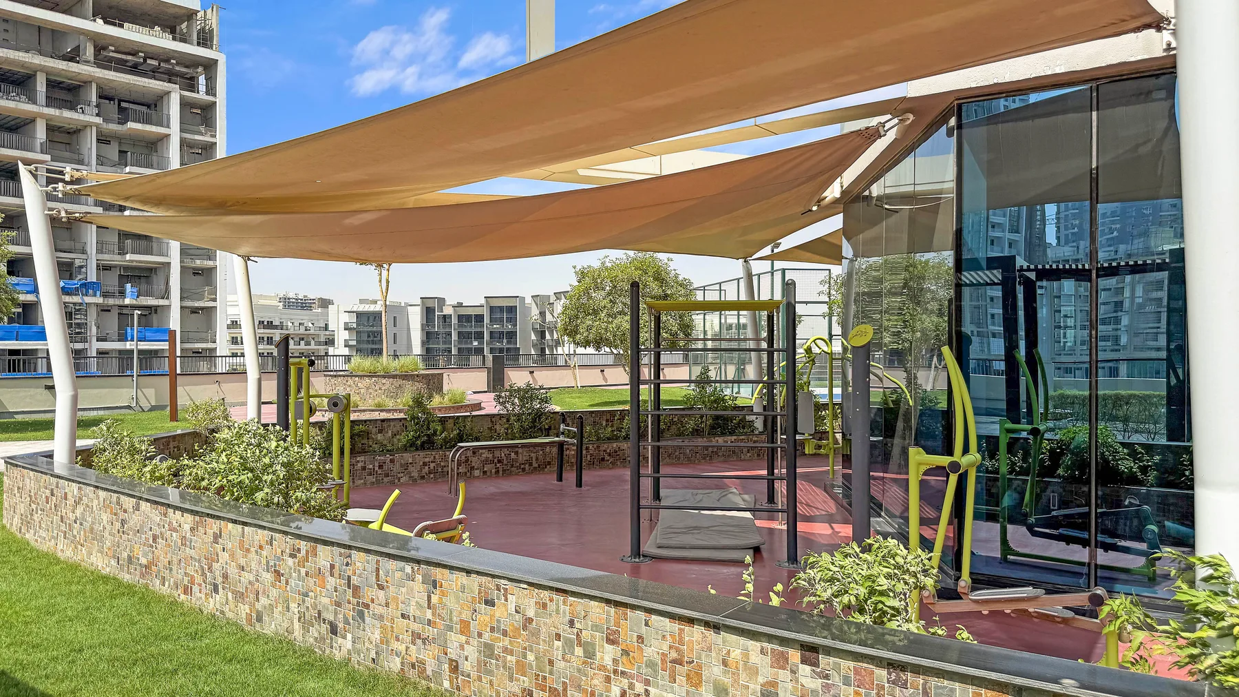 Una zona de ejercicio al aire libre con aparatos bajo una amplia cubierta de sombra.