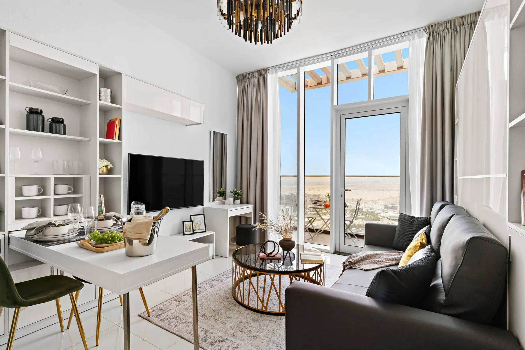 Una luminosa sala de estar y comedor con televisor y grandes ventanas con vistas al paisaje.